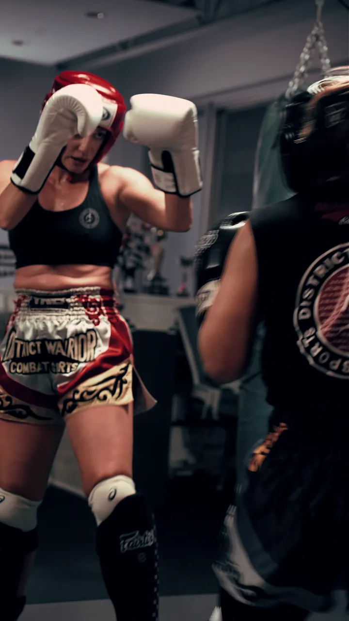 A member in headgear and District Warrior shorts during a Muay Thai class